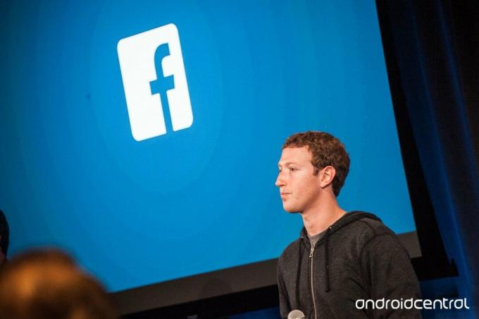 Mark Zuckerberg a Facebook embléma előtt