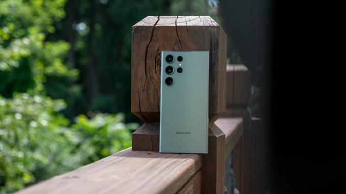 Žalias Samsung Galaxy S23 Ultra remiasi į medinį denio turėklą
